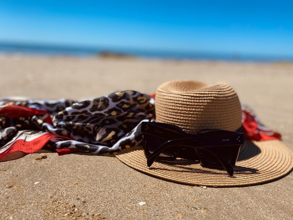 Foulard en soie disposé sur la plage avec un chapeau